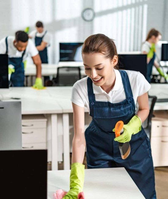 cheerful-cleaner-in-overalls-cleaning-office-desk-D4PQWDR